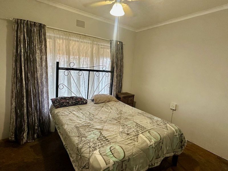 A functional bedroom featuring a ceiling fan, coved cornicing, and built-in storage, offering a neutral canvas for potential updates.