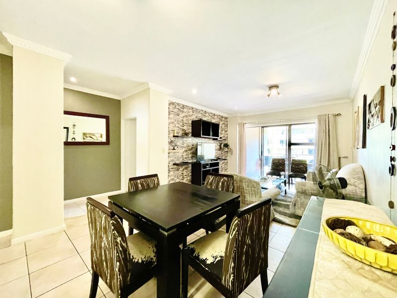 Spacious open-plan living and dining area featuring tiled floors, a decorative stone-cladding feature wall, and large sliding doors leading to the exterior.