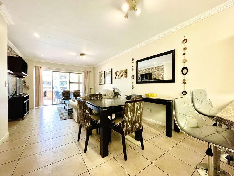 Open-plan living and dining area featuring tiled flooring, ceiling cornicing, and a large sliding glass door providing access to the balcony.