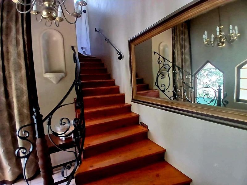 An elegant entryway featuring a wooden staircase with a decorative wrought iron balustrade and a built-in wall niche.