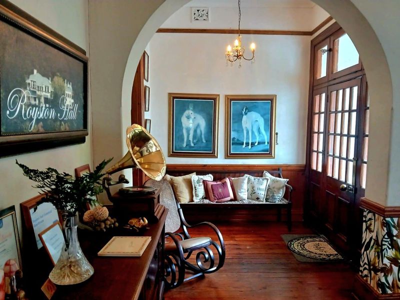 A welcoming entrance hall featuring polished timber flooring, classic timber paneling, a decorative archway, and a traditional timber-framed glass front door.