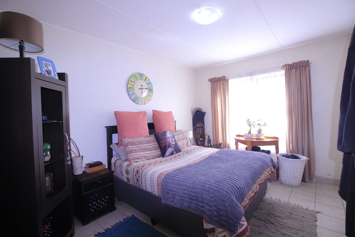 A functional bedroom featuring tiled flooring, neutral wall finishes, and natural light provided by a window with curtain rails.