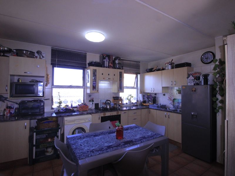 A functional kitchen featuring built-in cabinetry, laminate countertops, a built-in oven, hob, and integrated laundry plumbing, finished with tiled flooring.