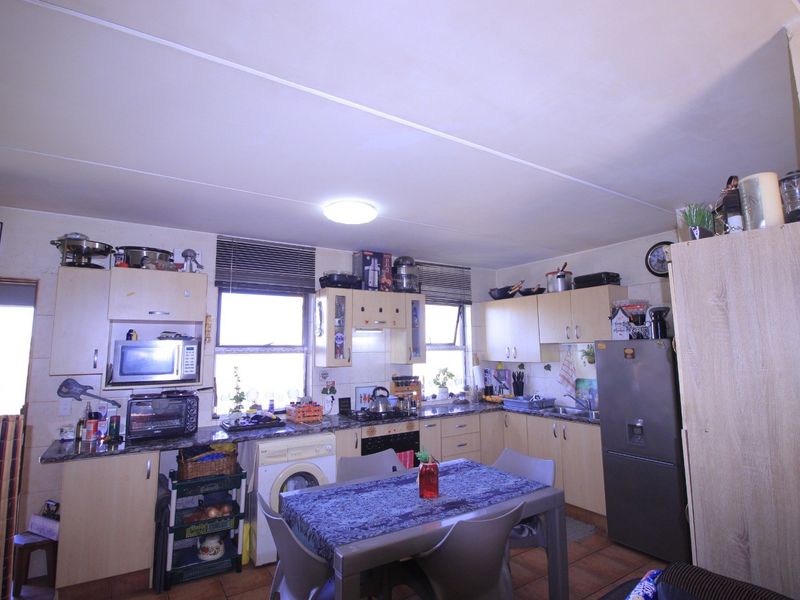 A functional kitchen featuring built-in cabinetry, laminate countertops, a hob with extractor fan, and tiled flooring, offering a practical layout for daily meal preparation.