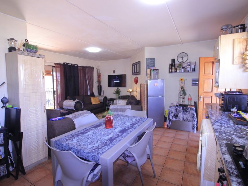 Open-plan living and dining area featuring tiled flooring, a functional kitchen with granite countertops, and direct access to an outdoor balcony.