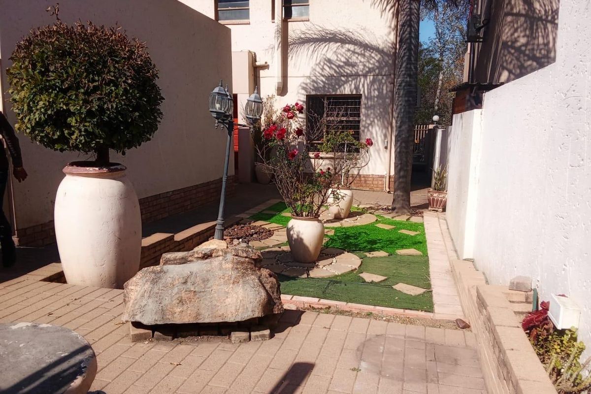 A private rear courtyard featuring a paved patio area, artificial grass section, and perimeter boundary walls with security features.
