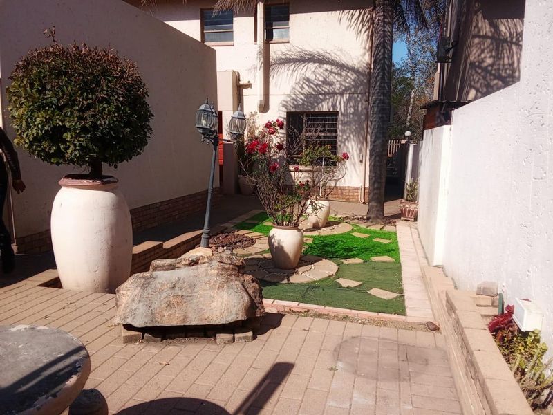 A private rear courtyard featuring a paved patio area, artificial grass section, and perimeter boundary walls with security features.