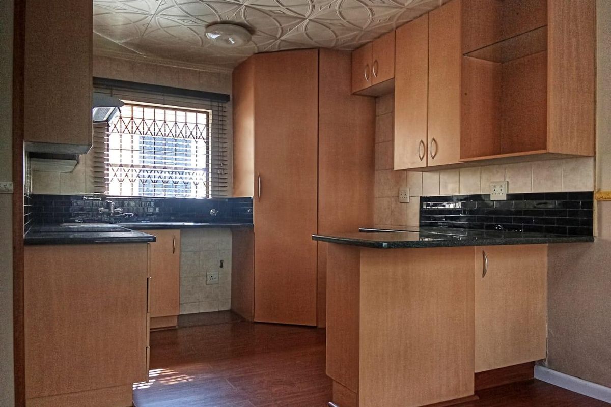 A functional kitchen featuring laminate cabinetry, granite countertops, and a subway tile backsplash, offering a clean, blank canvas for potential modern updates.