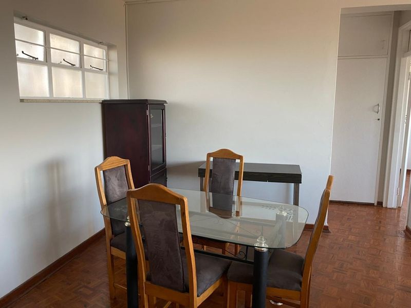 A dining area featuring classic parquet flooring, a casement window, and a built-in storage cupboard, offering a functional space for meals.