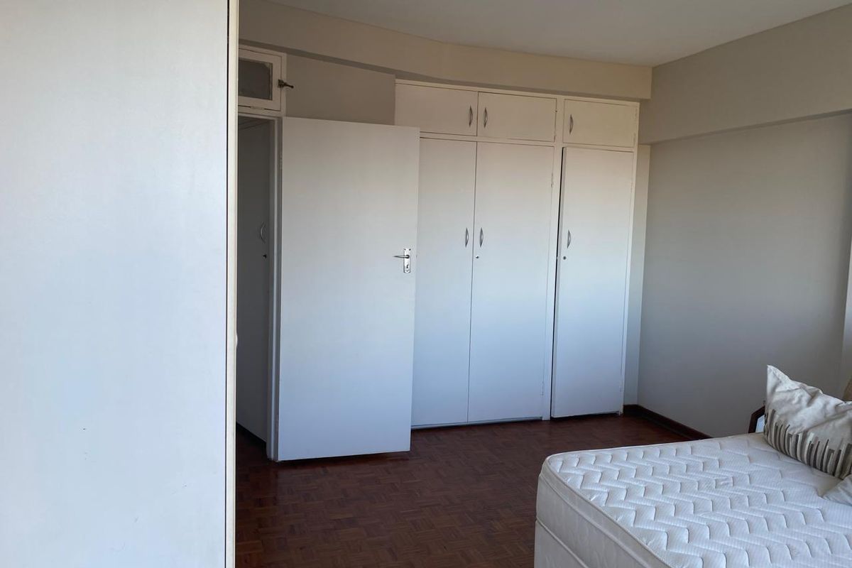 A bedroom featuring classic parquet flooring and ample built-in cupboard storage space.