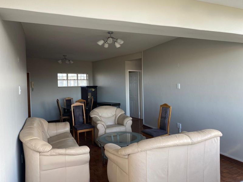 Spacious open-plan living and dining area featuring parquet flooring and neutral wall finishes, offering a versatile layout for modern living.