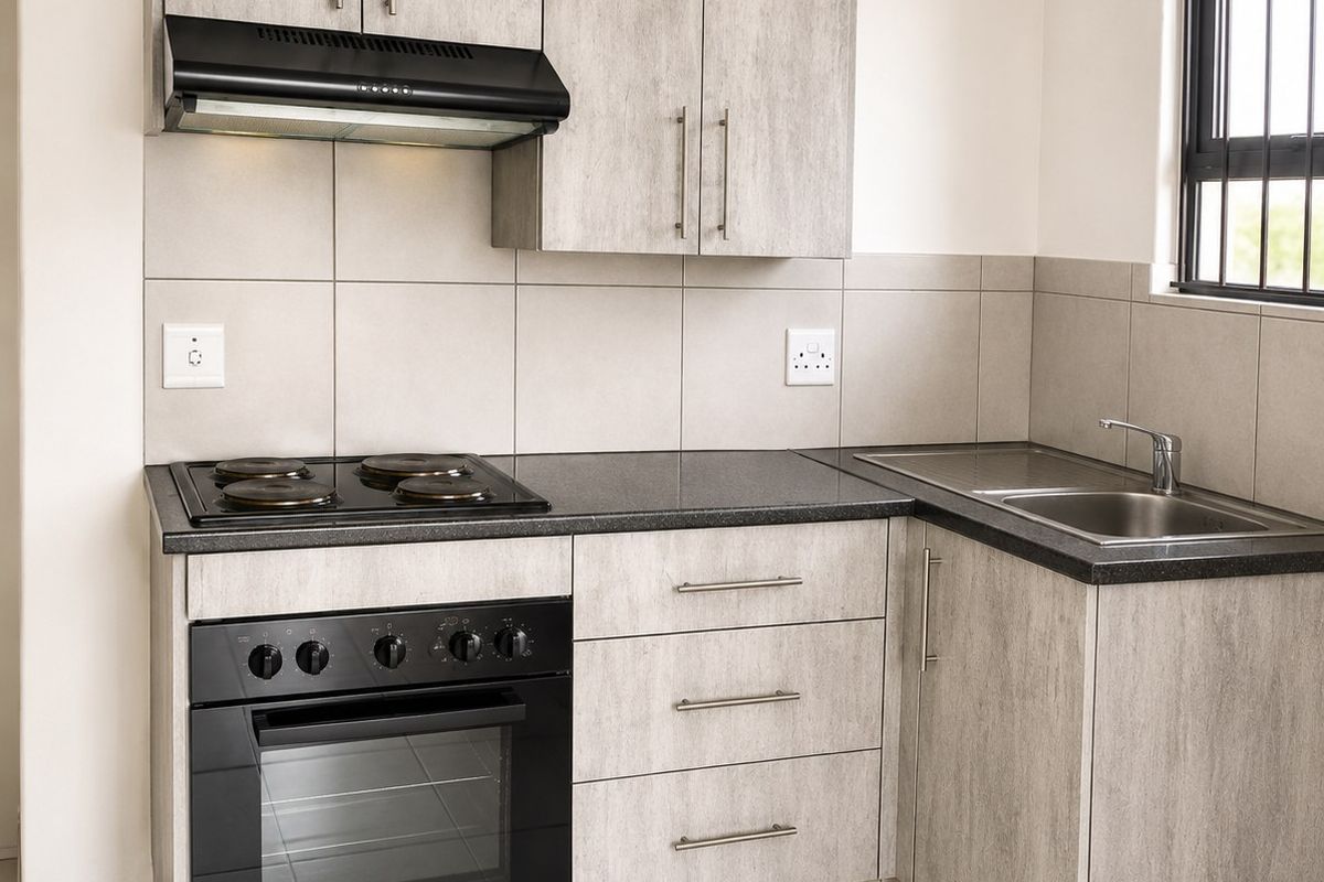 Modern kitchen featuring light wood-grain cabinetry, dark countertops, built-in oven and hob, extractor fan, and stainless steel sink with tiled finishes.