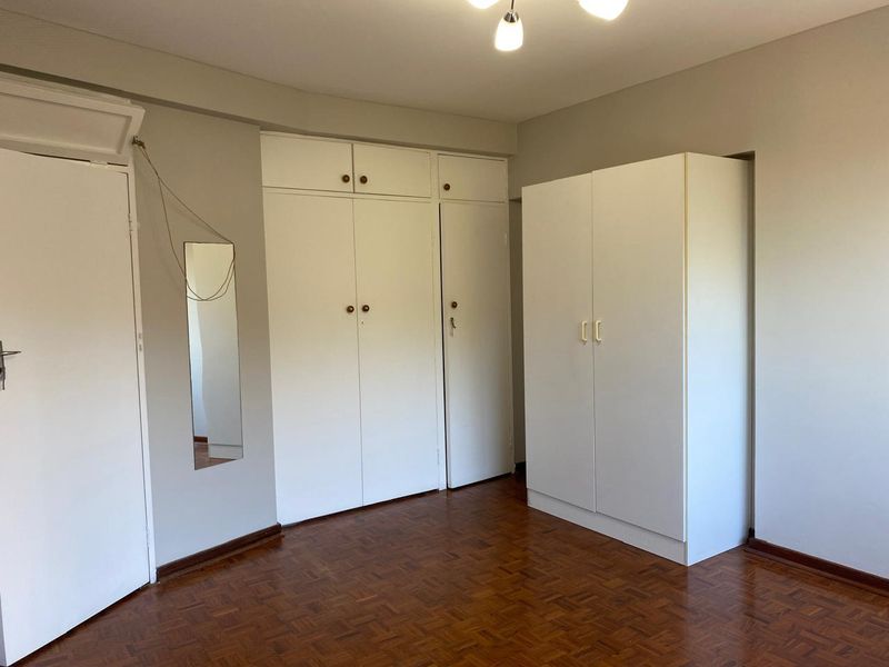 Bedroom featuring classic parquet flooring and ample built-in cupboard storage space.