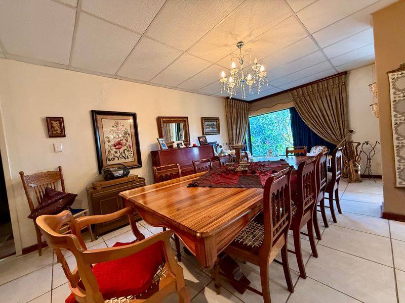 Spacious dining room featuring ceramic floor tiles, a drop ceiling, and a crystal chandelier, offering a traditional layout with large window access.