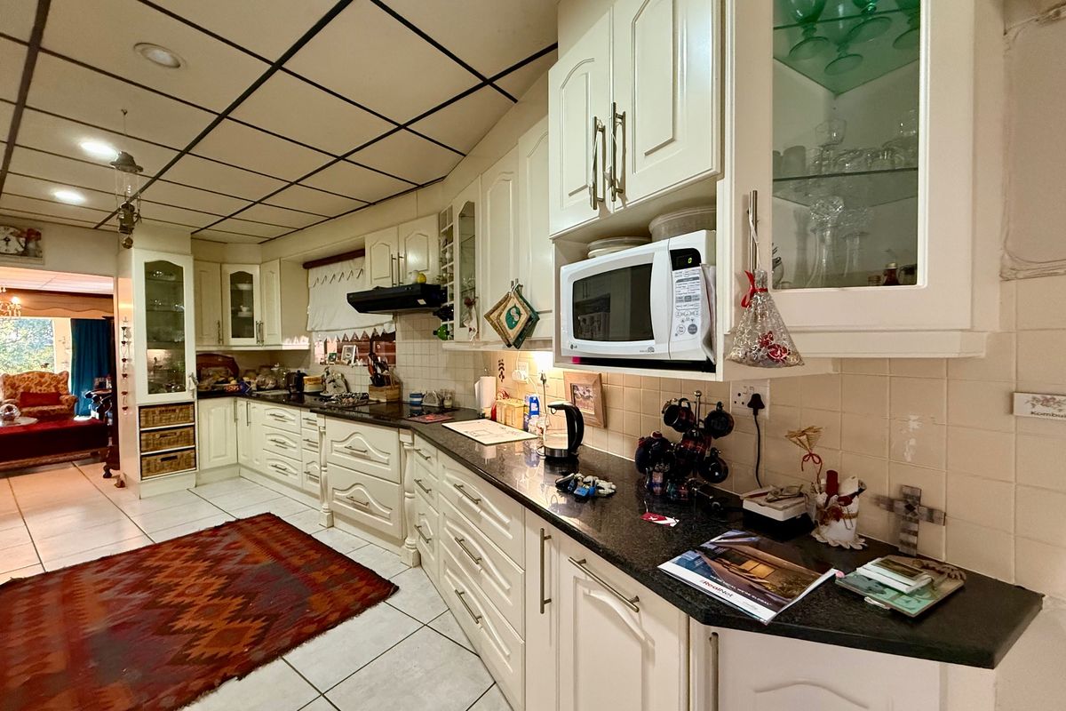 A spacious kitchen featuring extensive built-in cabinetry, granite countertops, a tiled backsplash, and a drop ceiling, offering a functional layout with ample storage.