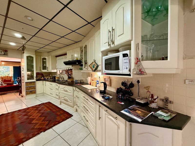 A spacious kitchen featuring extensive built-in cabinetry, granite countertops, a tiled backsplash, and a drop ceiling, offering a functional layout with ample storage.