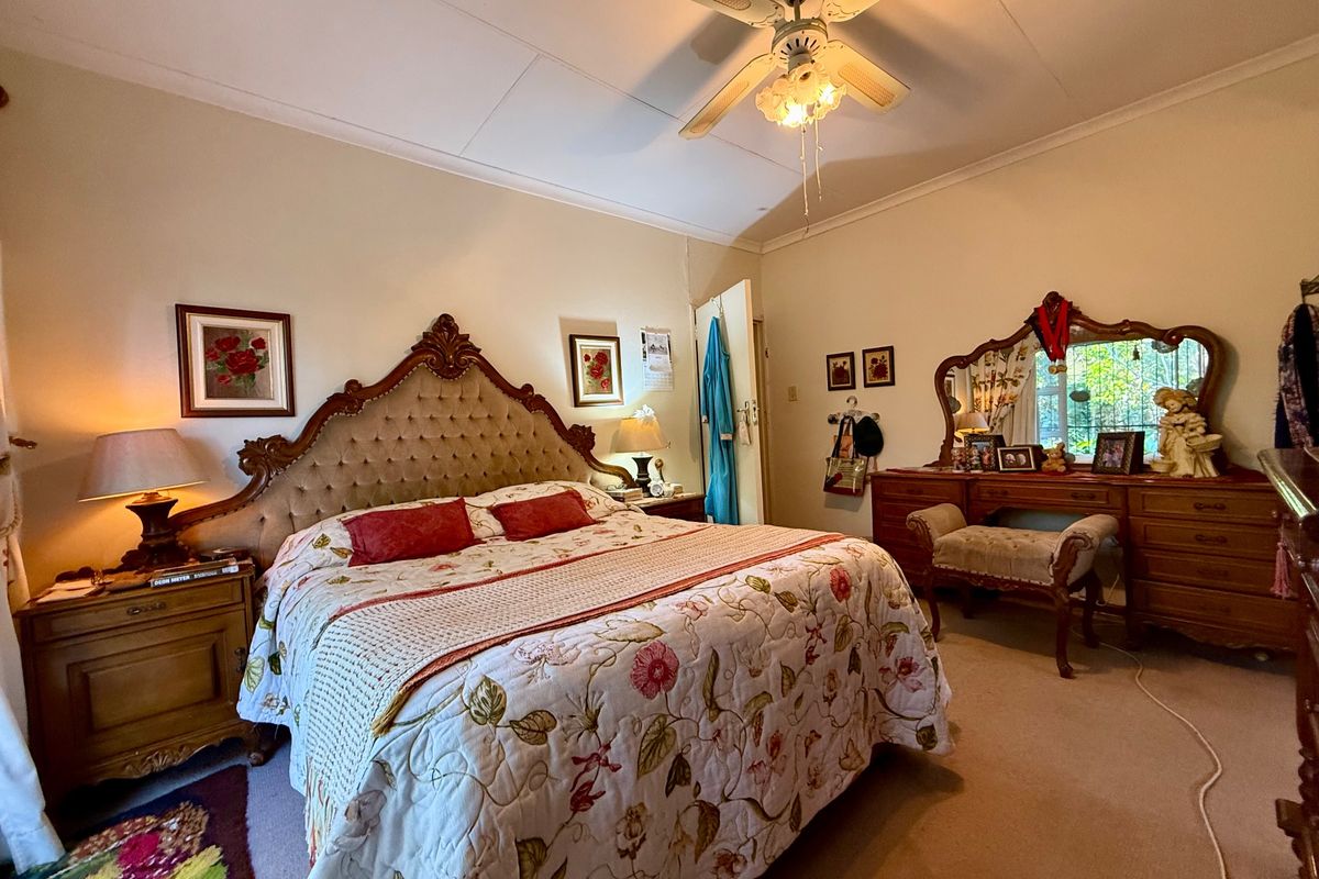 A spacious bedroom featuring a ceiling fan and a built-in vanity unit, offering a comfortable and functional living space.