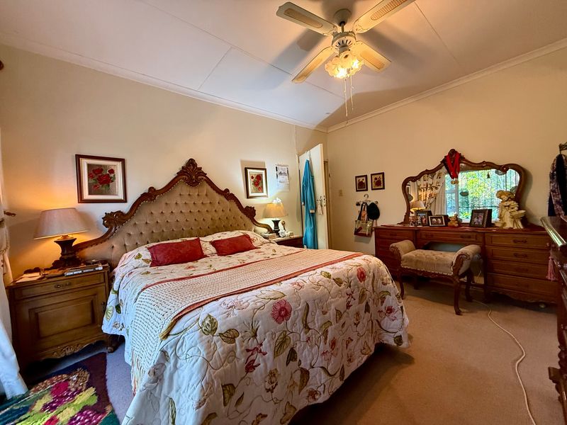 A spacious bedroom featuring a ceiling fan and a built-in vanity unit, offering a comfortable and functional living space.