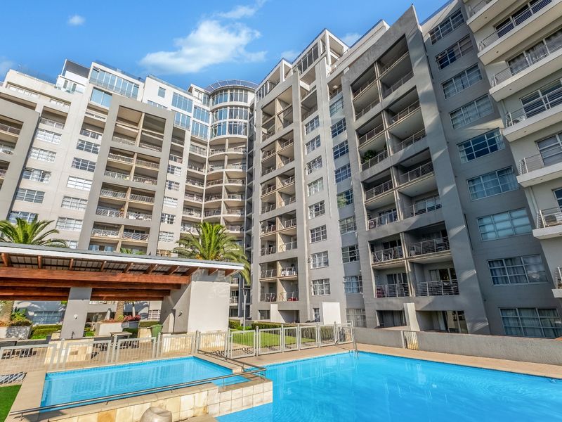 A well-maintained apartment complex featuring a central swimming pool, timber pergola, and multiple levels of private balconies with metal railings.