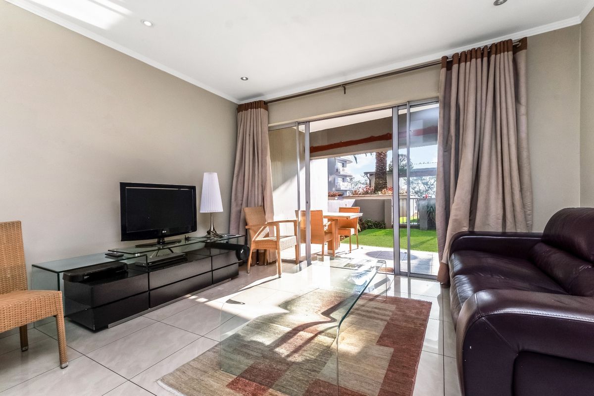 Bright living room featuring tiled flooring and large sliding glass doors that provide seamless access to the outdoor patio and garden area.