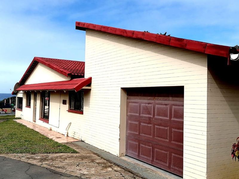 Exterior view of the townhouse featuring a tiled roof, brick facade, and an integrated garage with a paved driveway.