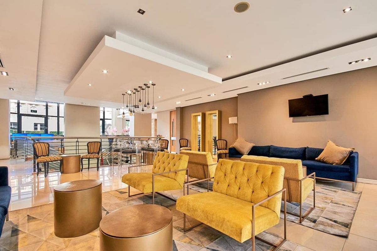 A spacious, modern living area featuring a stylish drop ceiling with recessed lighting, tiled floors, and a contemporary metal balustrade overlooking the lower level.
