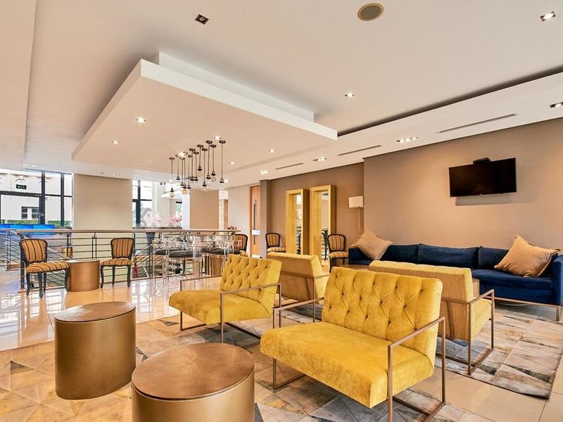 A spacious, modern living area featuring a stylish drop ceiling with recessed lighting, tiled floors, and a contemporary metal balustrade overlooking the lower level.