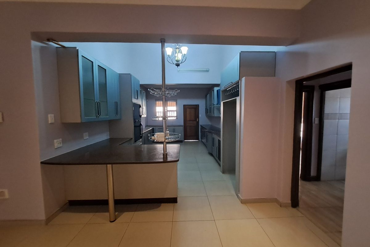 Spacious kitchen featuring extensive built-in cabinetry, a breakfast bar, and tiled flooring, offering a functional layout ready for modern updates.