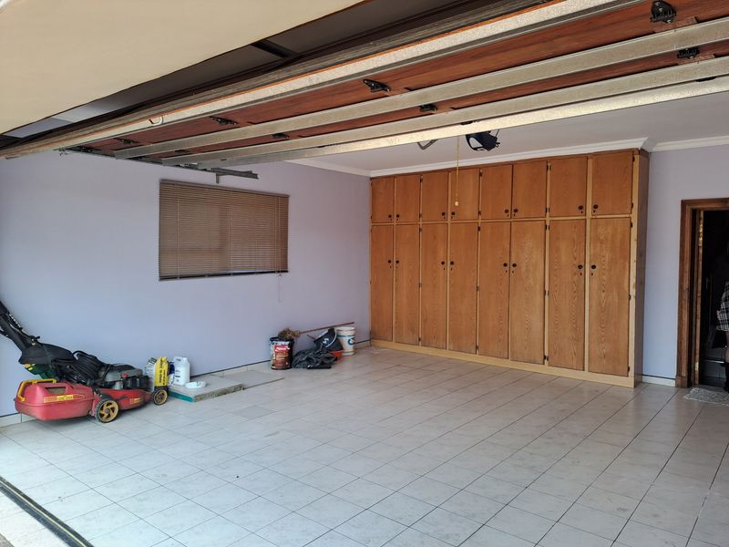 Spacious garage featuring tiled flooring, a sectional overhead door, and extensive built-in wooden storage cabinetry.