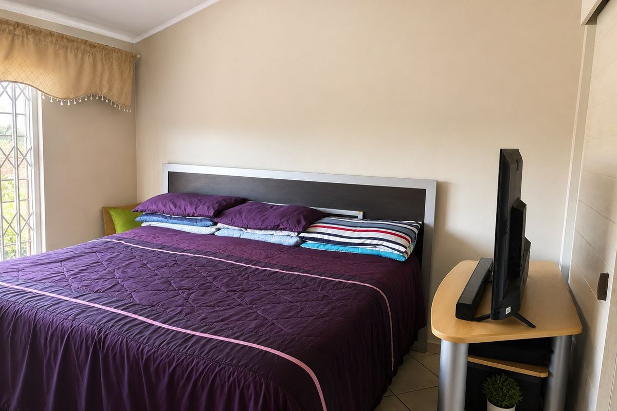 A functional bedroom featuring tiled flooring, a security gate on the window, and a sliding door entrance.