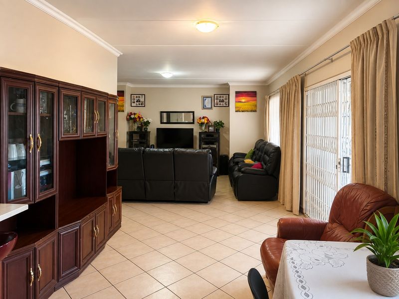 Spacious living area featuring ceramic floor tiles, decorative ceiling cornicing, and sliding glass doors with security gates providing access to the exterior.