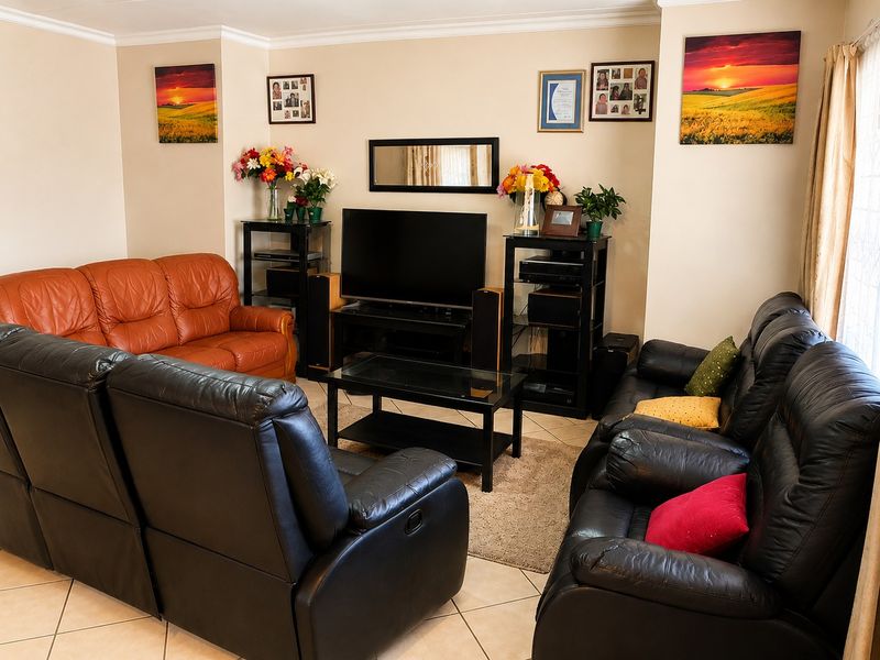 A comfortable living room featuring neutral wall tones, tiled flooring, and crown molding, providing a functional space for relaxation and entertainment.