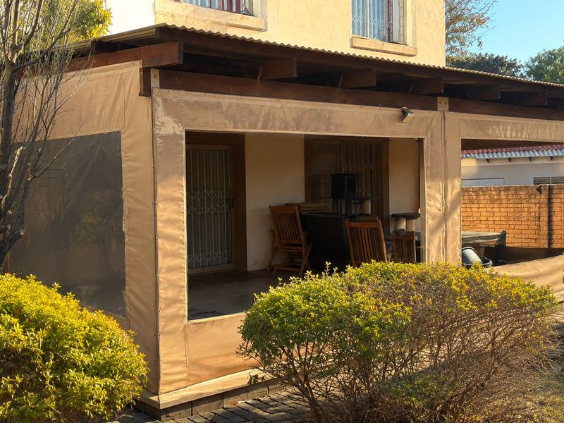 Covered patio area featuring a timber pergola structure with protective canvas drop-down blinds, providing a sheltered outdoor space for relaxation.