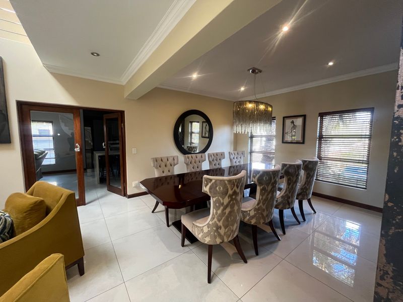 Spacious dining area featuring polished porcelain floor tiles, recessed downlighting, and elegant crown molding, creating a bright and well-maintained formal entertaining space.