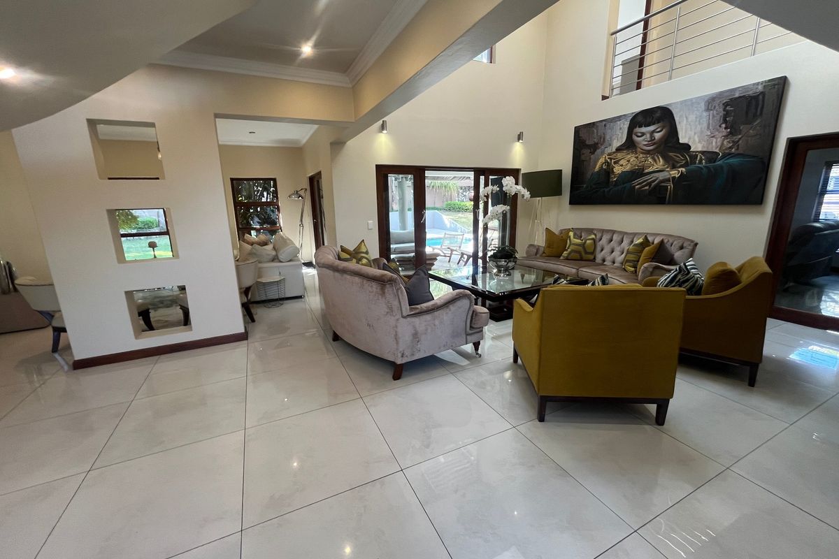 Spacious double-volume living area featuring large format floor tiles, recessed wall niches, and direct access to the outdoor patio area.