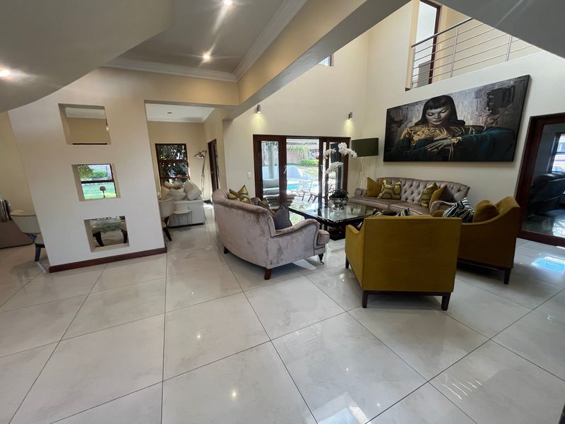 Spacious double-volume living area featuring large format floor tiles, recessed wall niches, and direct access to the outdoor patio area.