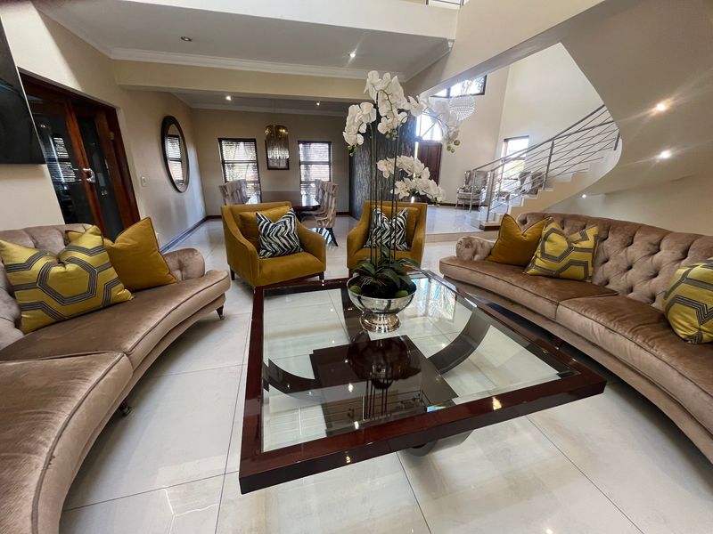 Spacious open-plan living area featuring polished tile flooring, a striking curved staircase with modern balustrade, and elegant recessed lighting throughout.