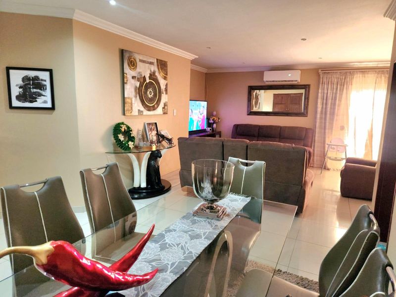 An open-plan living and dining area featuring tiled flooring, recessed downlighting, and a wall-mounted split-system air conditioner.