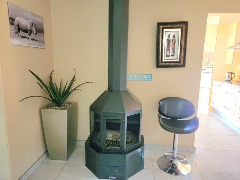 A living area featuring a central freestanding fireplace and tiled flooring, with a view through to the adjacent kitchen area.