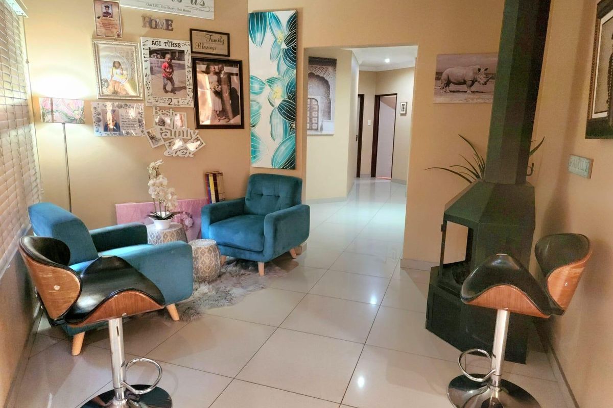 A living area featuring tiled flooring and a prominent freestanding fireplace, leading into a hallway with access to other rooms.
