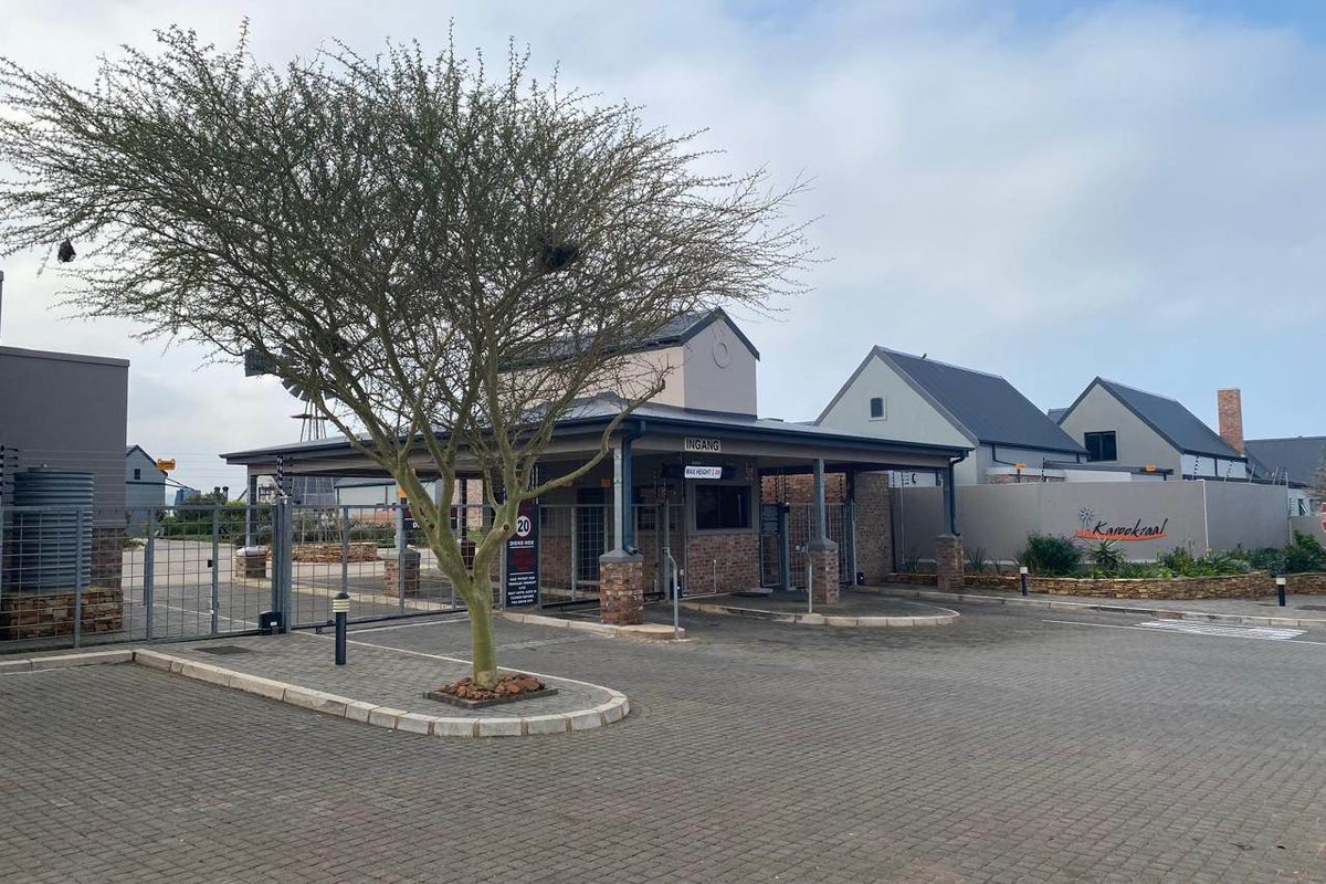 The main entrance and security gatehouse of the Karookraal estate, featuring paved driveway access and secure perimeter fencing.
