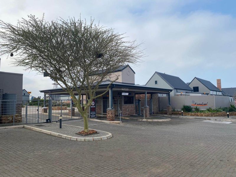 The main entrance and security gatehouse of the Karookraal estate, featuring paved driveway access and secure perimeter fencing.