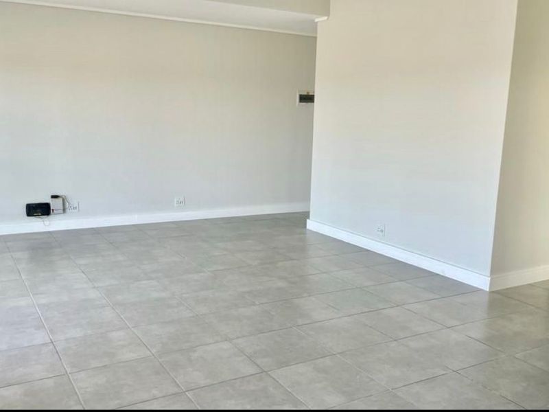 A bright, open-plan living area featuring neutral wall finishes, modern ceramic floor tiles, and clean architectural lines, ready for personalization.