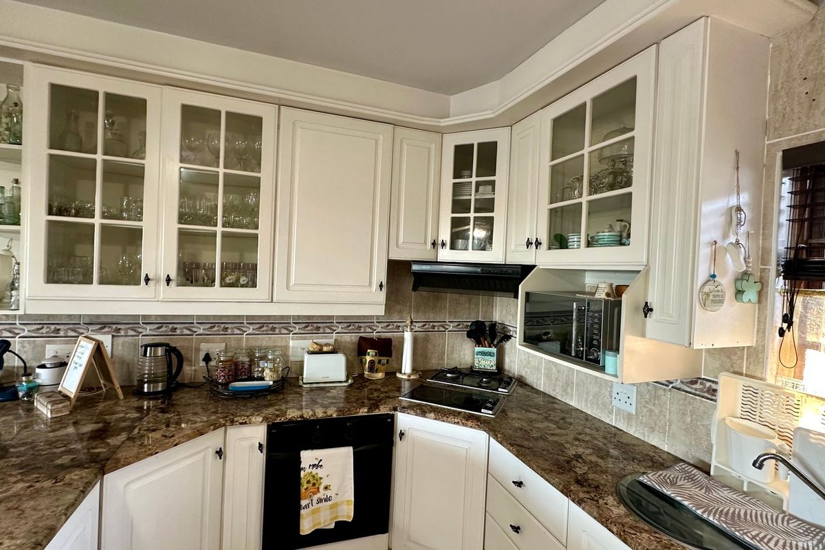 A functional kitchen featuring white cabinetry, granite countertops, a tiled backsplash, and integrated appliances including an oven and cooktop.