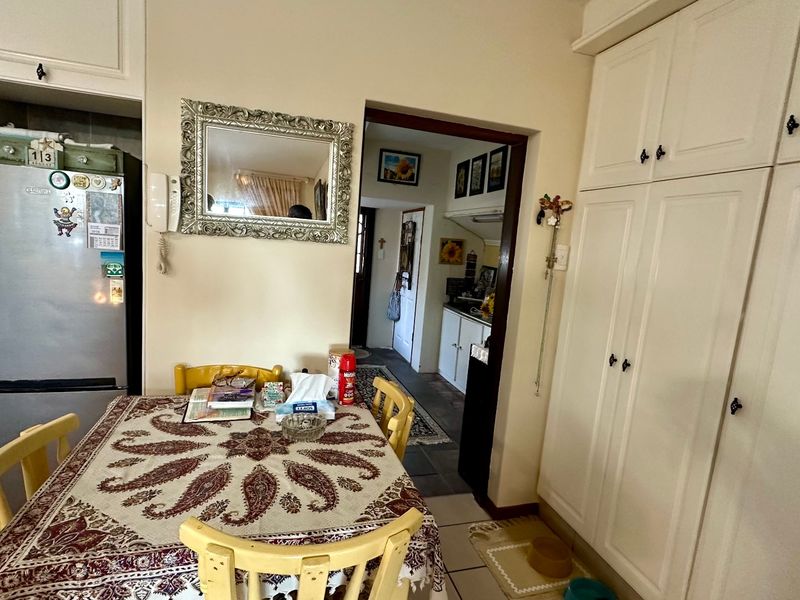 A functional kitchen area featuring built-in cabinetry and tiled flooring, with a view through to an adjacent scullery or utility space.