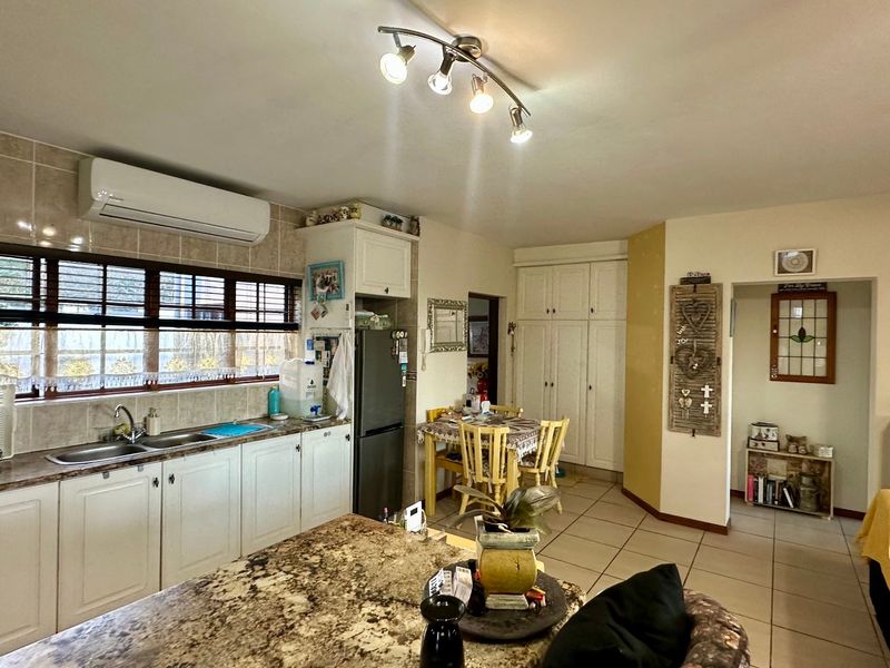 Open-plan kitchen and living area featuring granite countertops, double basin sink, tiled flooring, and built-in cabinetry with integrated storage.