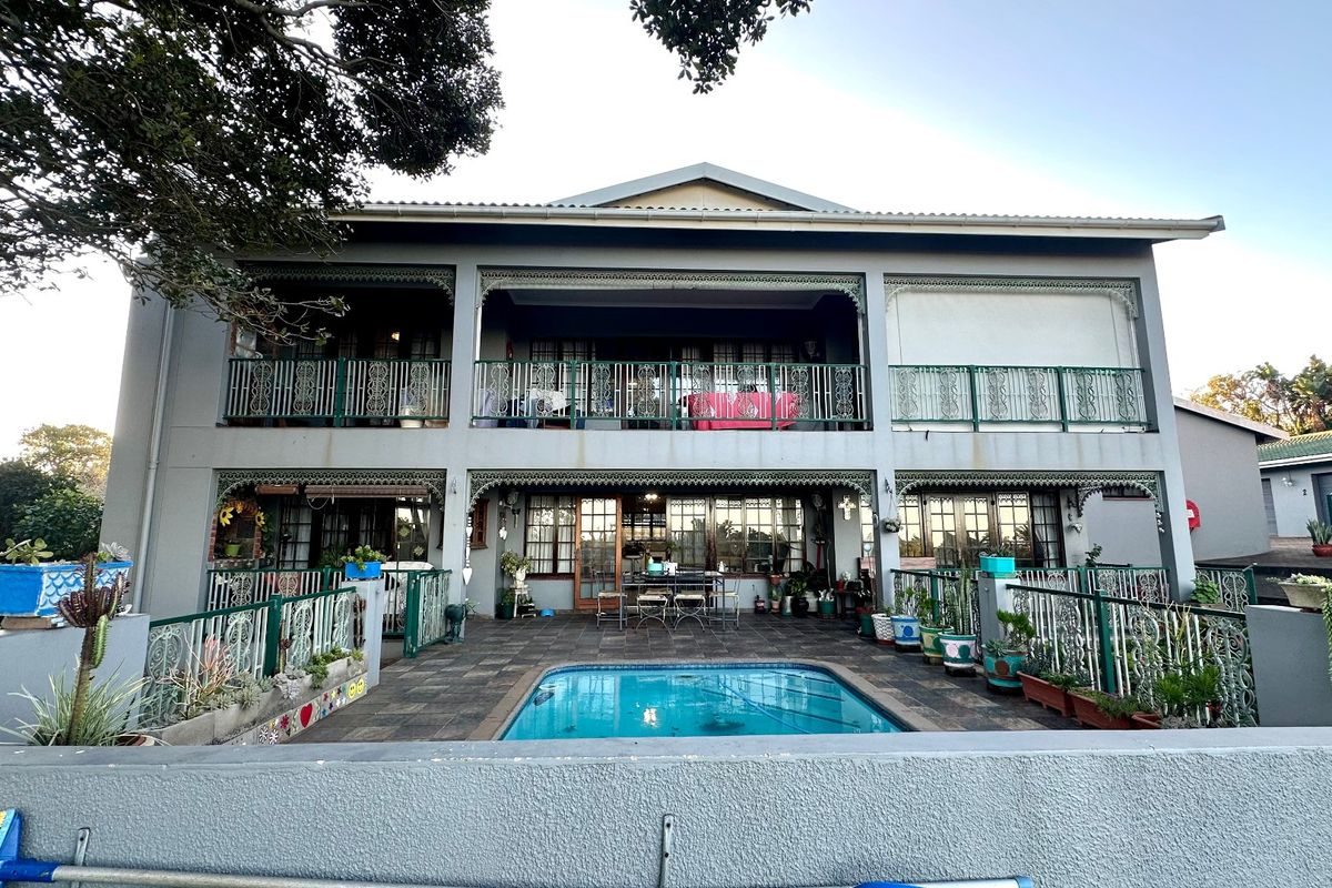 Rear view of a double-story townhouse featuring a swimming pool, paved patio area, and upper-level balconies with decorative wrought iron railings.