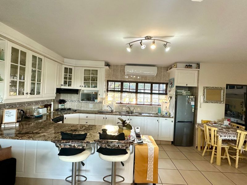 Spacious open-plan kitchen featuring granite countertops, ample built-in cabinetry, and tiled flooring, seamlessly flowing into the dining area.