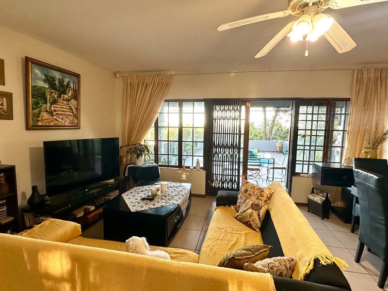 Open plan living and dining area featuring tiled floors, a ceiling fan, and large sliding doors providing access to an outdoor patio space.