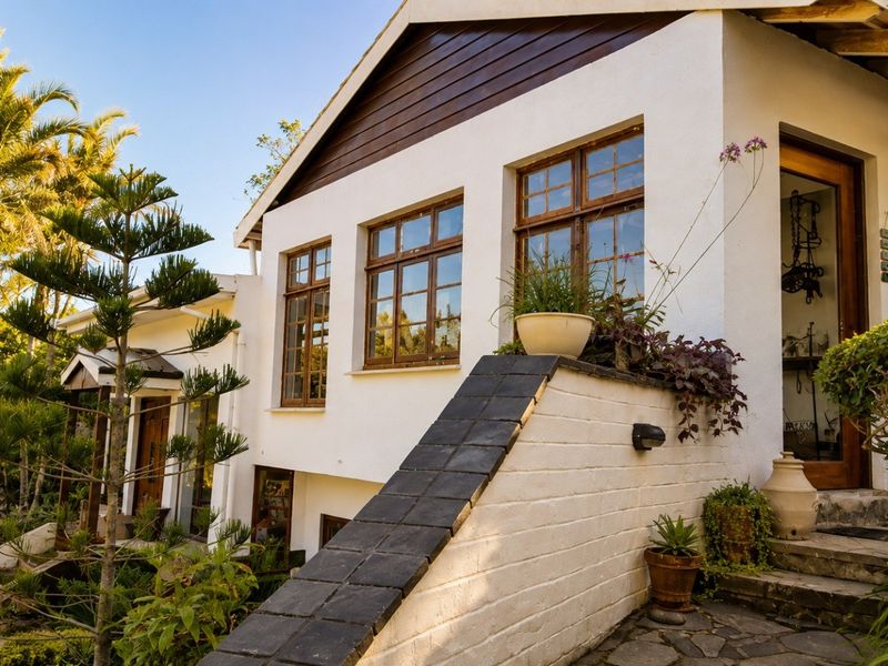 A charming exterior view of the home featuring timber-framed windows, stone paving, and a tiered garden entrance with classic architectural character.